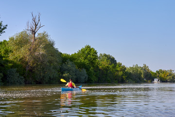 Man in blue kayak paddling in Danube river at spring
