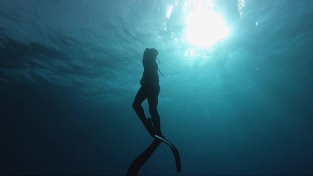 free dive slow motion shot of diver surfacing from deep underwater, fins flexing beautifully.