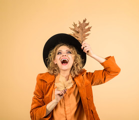 Fall. October. Woman autumn fashion. Happy woman with autumn leaves in orange jacket. Autumn girl in black hat. Fashionable woman with autumn leaves in hand. Beautiful model girl with autumnal leaves.