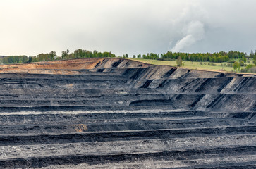 A large quarry with many horizons and ledges. Vertical bedding of coal seams.
