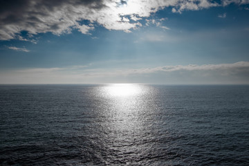 Sun shinning over the sea’s horizon on partially sunny day in England, UK.
