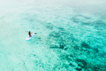 Woman paddling on sup board and enjoying turquoise transparent water and coral reef. Tropical travel, wanderlust and water activity concept. View from back. - 290655823