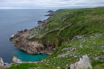 Green grassy cliffs on the shorelines of Cornwall on a grey and cloudy day.