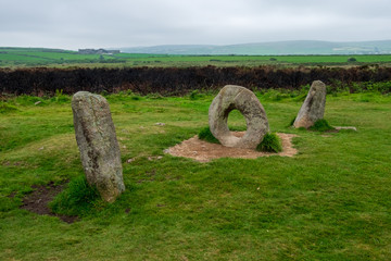 A unique rock structure that looks like the numbers 101 overlooks the green English countryside on this cloudy day.