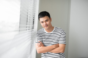 Happy Asian business man looking out of an office window.