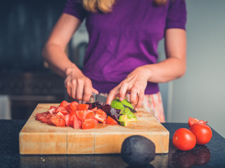Young woman preparing salad with tomatoes and avocado