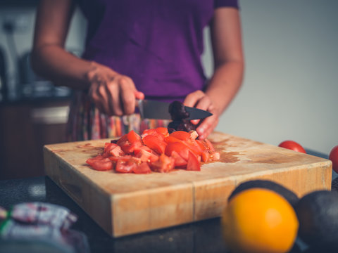 Young woman preparing salad with tomatoes and avocado