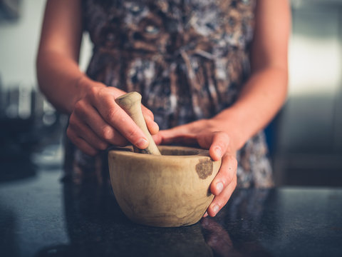 Young woman using pestle and mortar