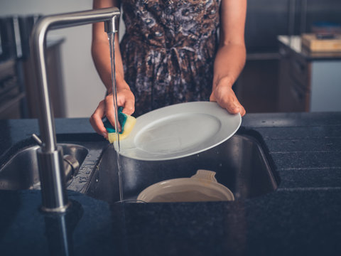 Young woman cleaning the dishes in her kitchen