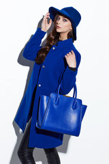High fashion portrait of young elegant woman. Blue coat, hat, bag.
