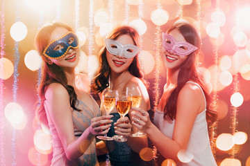 happy young group celebrating New Year and drinking champagne on masquerade party