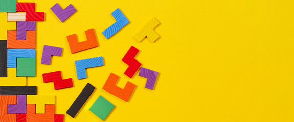 Different colorful shapes wooden blocks on yellow banner background. Top view