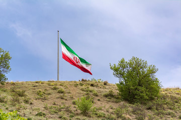 Huge  national flag of Iran on Tehran capital city countryside hillside 