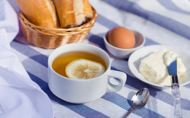 Breakfast on the grass. Green tea with lemon, bread with butter and egg for the traditional breakfast. French breakfast in the open air. 