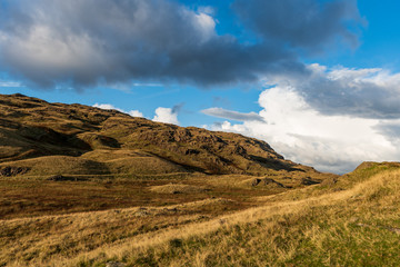 As the sun is setting it lights up the tall and rocky landscape in the Lake District, UK