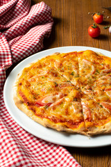 Fresh homemade Margarita pizza on a wooden background in composition with a red cloth and olive oil. Italian Cuisine. Selective focus on center of pizza