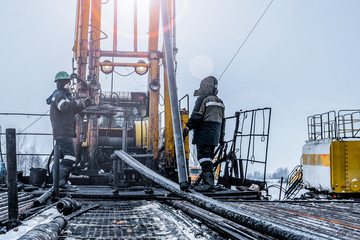 Naklejka premium Offshore oil rig worker prepare tool and equipment for perforation oil and gas well at wellhead platform. Making up a drill pipe connection. A view for drill pipe connection from between the stands