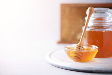 Honey dripping from wooden honey spoon in jar on grey background. Copy space. Autumn harvest concept.