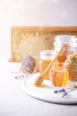 Herbal honey with lavender flowers, bee pollen granules, honey conb on grey background. Autumn harvest concept