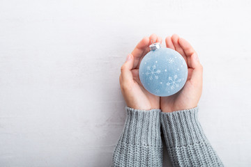 Christmas ball decor in women hand. Christmas greeting card. Woman's hands hold christmas or new year decorated gift.