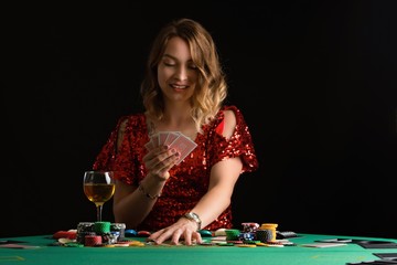 A young girl in a red evening dress plays poker in a casino. on a black background with space for design