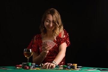 A young girl in a red evening dress plays poker in a casino. on a black background with space for design