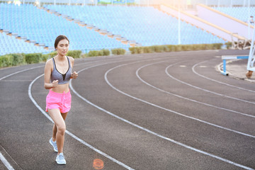 Sporty Asian woman running at the stadium