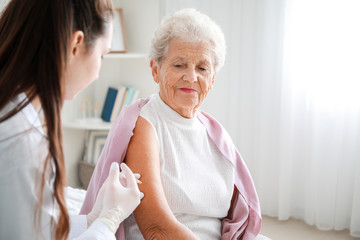 Doctor giving diabetic woman insulin injection at home