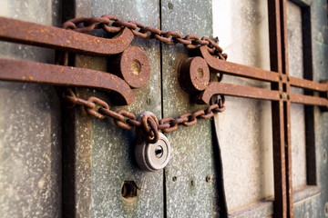 Old metallic padlock with rusty vintage chain hangs on old door, security concept