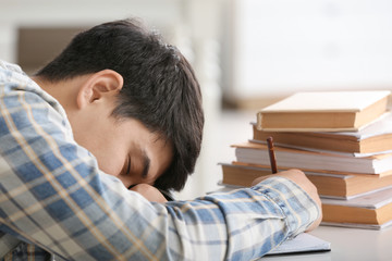 Fototapeta premium Tired Asian student sleeping at table