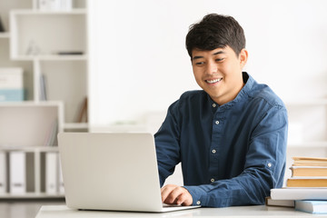 Asian student with laptop preparing for exam at home