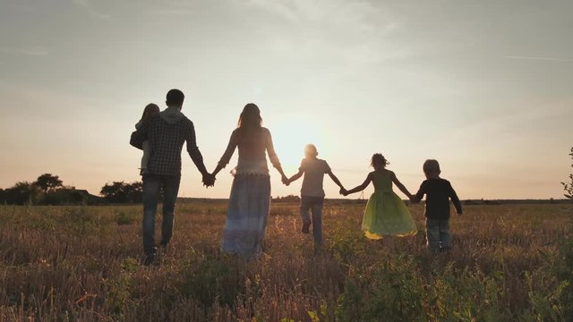 A large family of six people walk on the floor at sunset.
