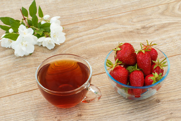 Glass cup of green tea with white jasmine flowers and strawberries.