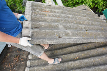 Asbestos removal roofer roof works. House with old, danger asbestos roof tiles repair and...
