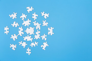 Unfinished white jigsaw puzzle pieces on blue background,  Copy space.