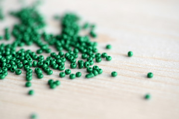 Closeup of green seed beads scattered on a wooden surface