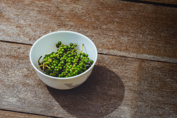 fresh green pepper corns in vine on wooden table