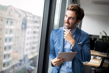Fototapeta premium Portrait of confident young businessman using digital tablet