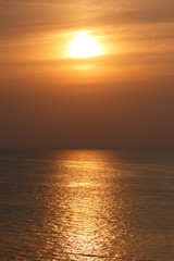 Golden color sunset on sea. Landscape with sun and dusk light sky with sun reflection on water surface.