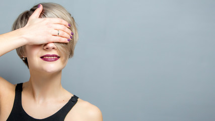 Beautiful woman with short hair hiding eyes. Young woman in casual clothing covering face with hand