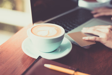 Coffee cup on wooden table and laptops,notebooks.
