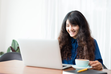 Fototapeta premium Young woman or student using laptop sitting at coffee shop. Happy girl working online or studying and using notebook. Freelance business concept.