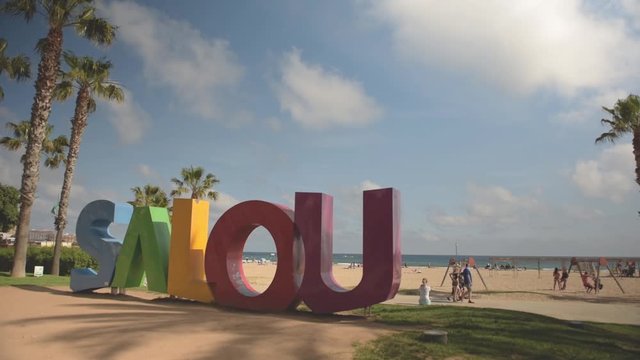 View to the Salou sign at the main beach with a woman sitting and looking around