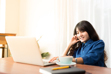 Young woman or student using laptop sitting at coffee shop. Happy girl working online or studying and using notebook. Freelance business concept.