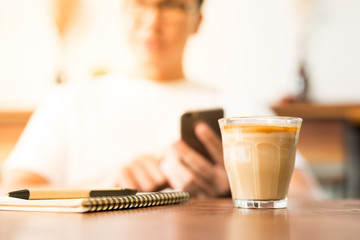 Businessman or owner using smartphone sitting in cafe and drinking coffee.