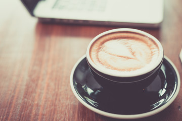 Coffee cup on wooden table and laptops,notebooks.