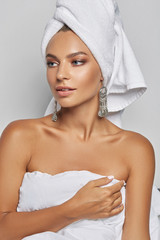 Three quarter cropped shot of a pretty and stylish young European woman with luxury hook earrings with a crowd of pendants with elaborate firebird patterns. 