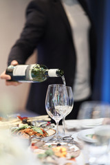 The waiter pours alcohol into a glass