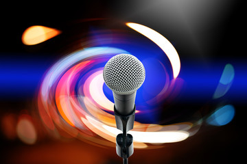High fidelity microphone with light trail.  Close up of high quality dynamic microphone  on stand with colorful light bokeh in background.