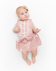 Portrait of a sweet infant wearing a pink dress, headband bow, isolated on white in studio.